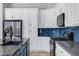 Spacious kitchen with a navy blue backsplash, stainless steel appliances, and white cabinets at 903 W Raven Dr, Chandler, AZ 85286
