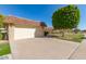 Well-maintained home featuring a brick garage, mature trees, manicured landscaping, and a spacious driveway at 10425 W Desert Forest Cir, Sun City, AZ 85351