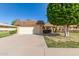 Well-maintained home featuring a brick garage, mature trees, manicured landscaping, and a spacious driveway at 10425 W Desert Forest Cir, Sun City, AZ 85351
