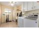 Bright laundry room featuring tile flooring, white cabinetry, and modern appliances for convenient chores at 10425 W Desert Forest Cir, Sun City, AZ 85351
