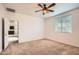 Neutral bedroom with carpet, ceiling fan, bright window and door to hallway at 10528 W Crown King Rd, Tolleson, AZ 85353