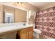 Bathroom with large mirror, vanity, and tiled shower with colorful patterned curtain at 1347 E Vernoa St, San Tan Valley, AZ 85140