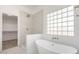 Bathroom showcasing a modern tub, walk-in shower, and a glass block window for natural light at 1430 E Douglas St, Casa Grande, AZ 85122