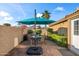 Backyard patio with dining area under a blue umbrella, complete with green foliage at 15149 W Vale Dr, Goodyear, AZ 85395