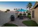 A backyard oasis with brick patio, a grill, and a dining set under a large blue patio umbrella at 15149 W Vale Dr, Goodyear, AZ 85395