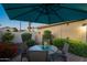Cozy patio dining with umbrella, surrounded by lush foliage, creating an intimate outdoor setting at 15149 W Vale Dr, Goodyear, AZ 85395