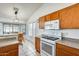 Bright kitchen featuring wooden cabinetry, white appliances, tile flooring, and breakfast nook at 16034 W Carmen Dr, Surprise, AZ 85374
