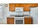 Kitchen with white appliances, wood cabinetry, and a view of the breakfast bar at 16034 W Carmen Dr, Surprise, AZ 85374
