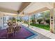 Inviting covered patio with comfortable seating and a view of the landscaped backyard and fountain at 16769 W Brookhaven Ct, Surprise, AZ 85387