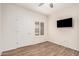 This bedroom has wood look tile flooring, a TV, ceiling fan, and bright natural light from the window at 17017 N 12Th St # 2012, Phoenix, AZ 85022