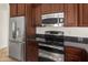 Kitchen appliances with stainless steel fridge and oven with dark wood cabinets and granite countertops at 18222 E La Posada Ct, Gold Canyon, AZ 85118
