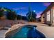 View of backyard pool and spa with rock waterfall feature and desert landscaping at dusk at 20933 N 70Th Dr, Glendale, AZ 85308