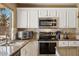 Updated kitchen with stainless steel appliances, granite countertops, and white cabinets at 2123 E Catclaw St, Gilbert, AZ 85296