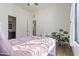 Bright bedroom with a pink quilt bed, a desk, and a large houseplant at 2285 E Chandler Heights Rd, Chandler, AZ 85249