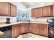 Kitchen area features wooden cabinets, modern appliances, double sink and window with plants at 2455 E Broadway Rd # 13, Mesa, AZ 85204