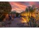 Inviting backyard patio with string lights, Adirondack chairs, and desert landscaping under a colorful sunset at 27654 N 125Th Dr, Peoria, AZ 85383