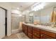 Bathroom with a walk-in shower, double sinks, light wood cabinets, and neutral tile at 27654 N 125Th Dr, Peoria, AZ 85383