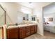 Bathroom featuring a double sink vanity, a large mirror, and access to the bedroom and toilet at 27654 N 125Th Dr, Peoria, AZ 85383