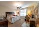 Comfortable bedroom featuring a ceiling fan, patterned bedding, and a seating area with a writing desk at 27654 N 125Th Dr, Peoria, AZ 85383