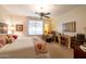 Cozy bedroom featuring a ceiling fan, patterned bedding, and a charming seating area with a writing desk at 27654 N 125Th Dr, Peoria, AZ 85383