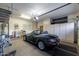The spacious garage features epoxy floors, built-in cabinets, and a dark green convertible at 27654 N 125Th Dr, Peoria, AZ 85383