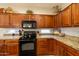 Stylish kitchen with wooden cabinets, granite countertops, and contemporary black appliances under natural light at 27654 N 125Th Dr, Peoria, AZ 85383