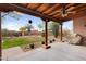 Expansive back patio with wood beam ceiling overlooks the lush yard and mature desert landscaping at 29204 N Bryce Trl, Queen Creek, AZ 85144