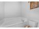 A well lit bathroom featuring a white soaking tub and a toilet with a rustic, patterned seat at 29204 N Bryce Trl, Queen Creek, AZ 85144