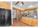 Open kitchen and dining area with terracotta tile, exposed beams, and black refrigerator at 29204 N Bryce Trl, Queen Creek, AZ 85144