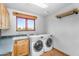 Functional laundry room with wooden cabinets, utility sink, and modern side-by-side washer and dryer at 29204 N Bryce Trl, Queen Creek, AZ 85144