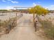 Desert property entrance featuring a rustic archway leading to a sprawling estate under a clear, blue sky at 29204 N Bryce Trl, Queen Creek, AZ 85144