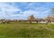 View of the home's vast, grassy backyard with mature trees and trucks at 3137 W Baseline Rd, Laveen, AZ 85339