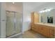 Well-lit bathroom featuring a shower, soaking tub, and wooden cabinets at 40314 W Marion May Ln, Maricopa, AZ 85138