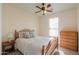 Cozy bedroom with wood furniture, a ceiling fan, and natural light from the window at 40314 W Marion May Ln, Maricopa, AZ 85138