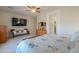 Bright bedroom with a TV, ceiling fan, and an ensuite bathroom entry at 40314 W Marion May Ln, Maricopa, AZ 85138