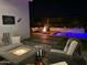 Nighttime view of an inviting backyard pool and lounging area with a cozy fireplace at 4457 E Fountain St, Mesa, AZ 85205