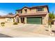 Two-story home showcasing desert landscaping, a green garage door, and a tile roof under a blue sky at 5749 S 249Th Dr, Buckeye, AZ 85326