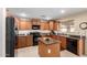 Kitchen featuring wooden cabinets, granite countertops, black appliances, and an island at 5749 S 249Th Dr, Buckeye, AZ 85326