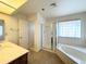 Bright bathroom featuring a bathtub with sliding shower doors and a large mirror at 8217 E Medina Ave, Mesa, AZ 85209