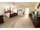 Spacious main bedroom with a four-poster bed, neutral carpet, and access to an ensuite bathroom at 8217 E Medina Ave, Mesa, AZ 85209