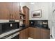 Kitchenette with dark wood cabinets, granite counters, stainless steel appliances, and stylish fixtures at 9735 E Kemper Way, Scottsdale, AZ 85255