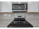 Stainless steel microwave and stove with tile backsplash at 18207 W Daley Ln, Surprise, AZ 85387