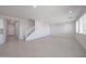 Bright open-plan living space with tile flooring, stairs, and natural light from the windows at 18207 W Daley Ln, Surprise, AZ 85387