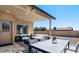 An outdoor patio featuring stylish seating arrangements, a dining table, and an overhead shade structure at 3747 E Harmony Ave, Mesa, AZ 85206