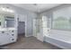 Well-lit bathroom featuring a double vanity, a glass-enclosed shower, and a soaking tub, with tile floors at 4059 E Mesquite St, Gilbert, AZ 85296