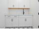 Laundry room featuring patterned tile flooring, white cabinets, and a stainless steel faucet at 1246 E Penedes Dr, Gilbert, AZ 85298