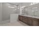 Well-lit bathroom with dual sinks, granite countertops, and glass-enclosed shower with tiled walls at 19323 W San Juan Ave, Litchfield Park, AZ 85340