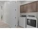 Laundry room with wooden cabinets, white washer and dryer, and a door to another room at 19323 W San Juan Ave, Litchfield Park, AZ 85340