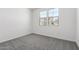 Well-lit bedroom with neutral carpet, white walls, and a view of neighboring houses through the window at 5011 W Hardtack Trl, Laveen, AZ 85339