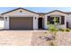 Well-maintained home featuring a two-car garage, brick paver driveway, and desert landscaping at 5011 W Hardtack Trl, Laveen, AZ 85339